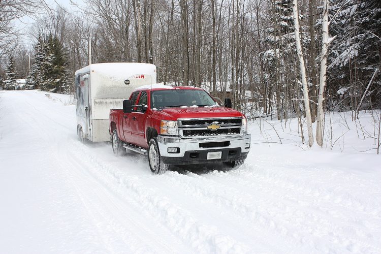 Pickup truck pulling a trailer on a snow-covered rural Wyoming highway in winter conditions - best truck tires for towing